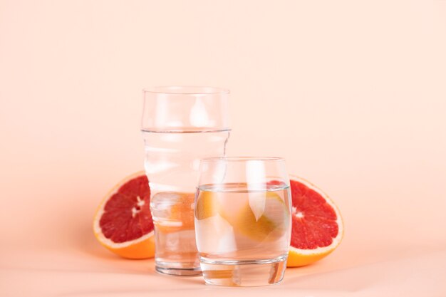 Foto gratuita rodajas de naranja roja con vasos de agua