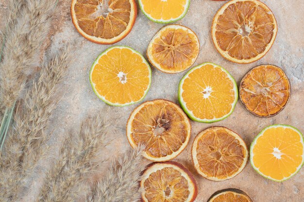 Rodajas de naranja secas y frescas sobre fondo de mármol.