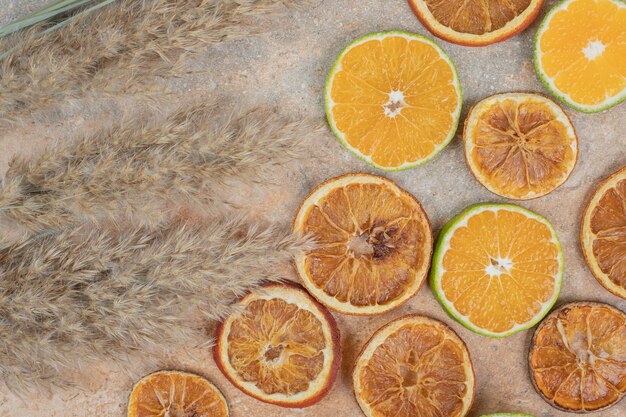 Rodajas de naranja secas y frescas sobre fondo de mármol.