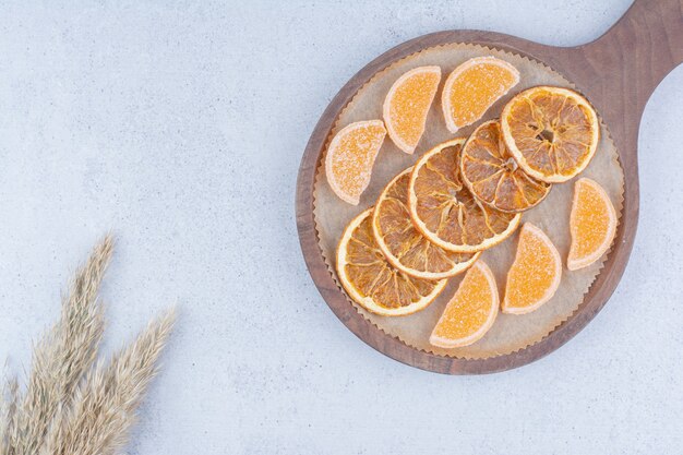 Rodajas de naranja secas y mermeladas sobre plancha de madera.