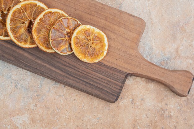 Rodajas de naranja secas sobre tabla de madera.