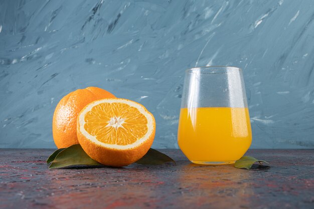 Rodajas de naranja y vaso de jugo, sobre la mesa mixta.
