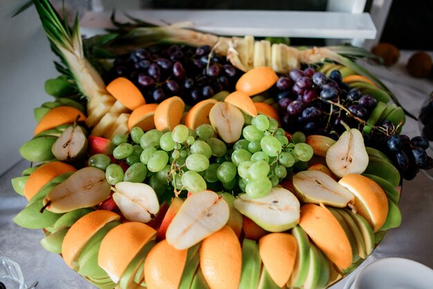 Rodajas de naranjas, peras, manzanas y uva servidos en un plato grande