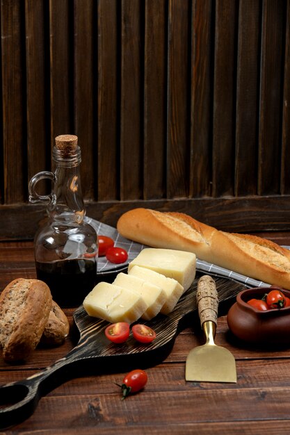 Rodajas de parmesano servidas en tablero de madera con baguette