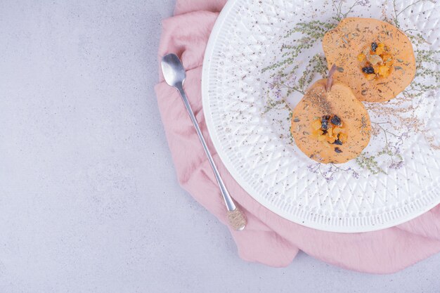 Rodajas de pera cocida con hierbas y especias en un plato blanco.