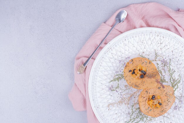 Rodajas de pera cocida con hierbas y especias en un plato blanco.