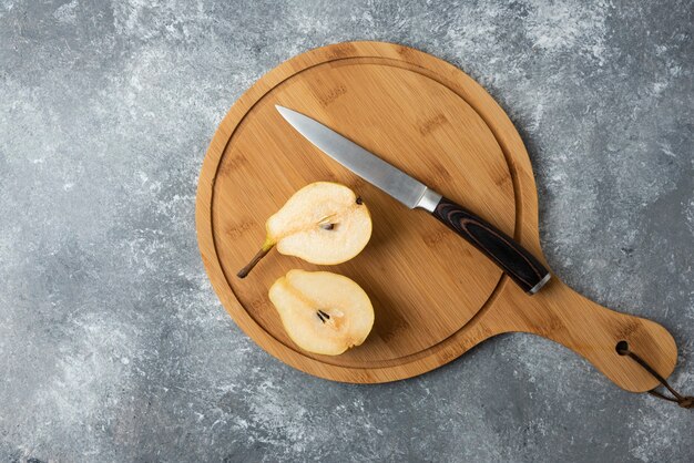 Foto gratuita rodajas de pera sobre una tabla de madera con un cuchillo.