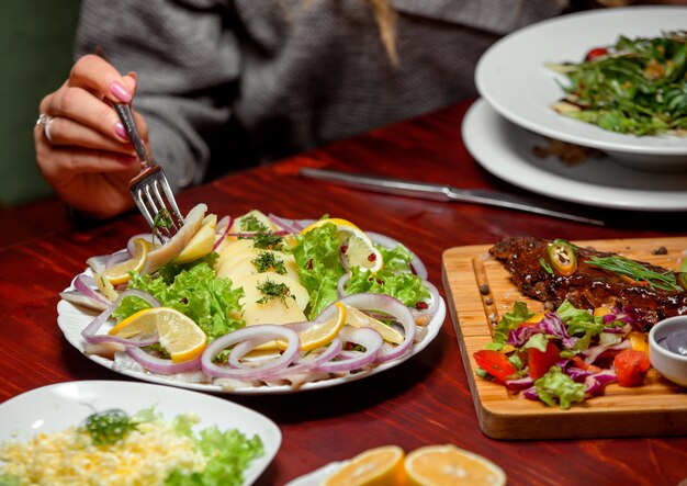 Rodajas de pescado con hierbas, cebollas y limones