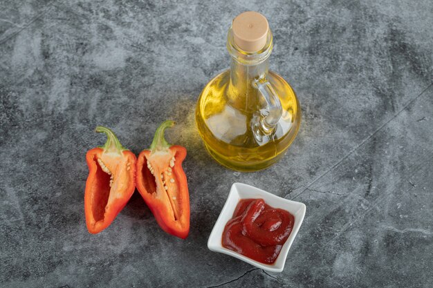 Rodajas de pimiento rojo con salsa de tomate sobre una superficie gris.