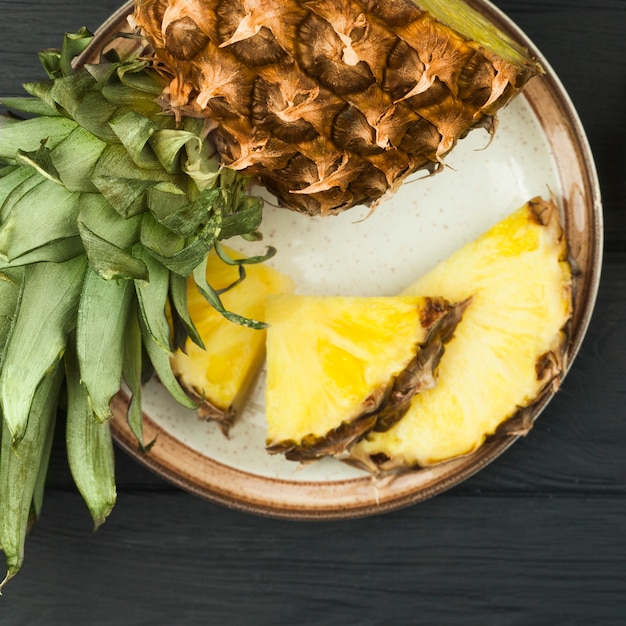 Rodajas de piña con hojas verdes en placa