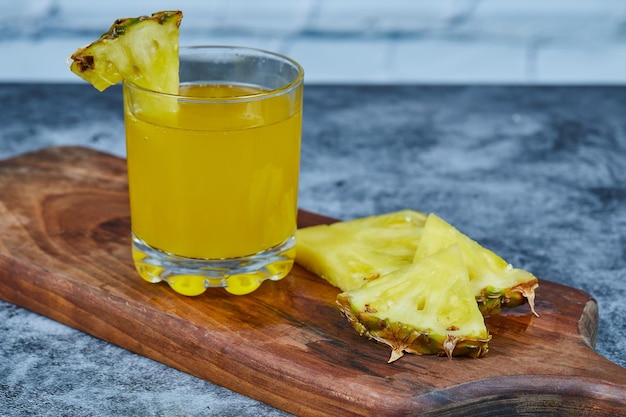 Foto gratuita rodajas de piña y jugo de piña sobre tabla de madera.