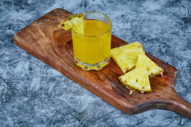 Rodajas de piña y jugo de piña sobre tabla de madera