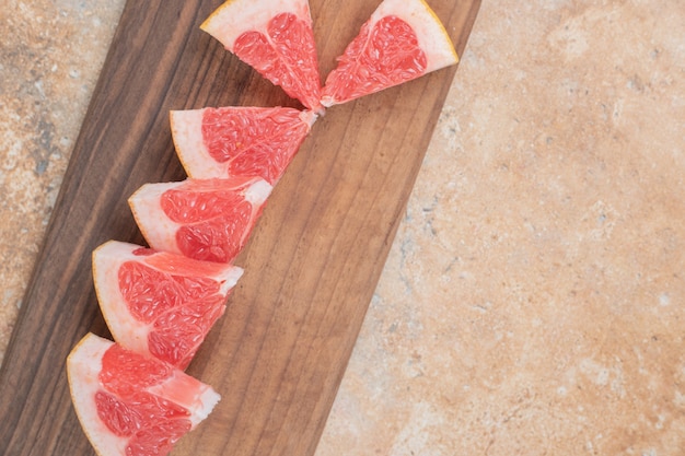 Rodajas de pomelo fresco sobre tabla de madera.