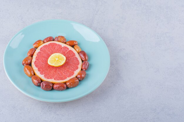 Rodajas de pomelo, limón y arándanos maduros en placa azul.