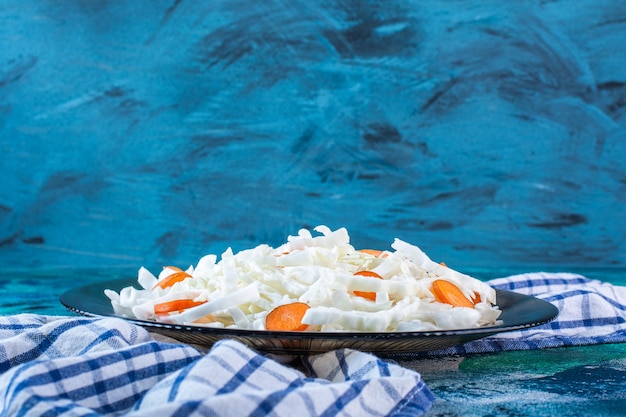 Foto gratuita rodajas de repollo y zanahorias en un plato sobre un paño de cocina