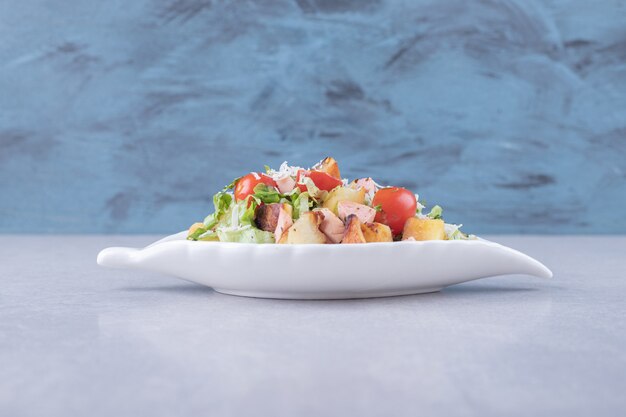 Rodajas de salchichas fritas y lechuga en un tazón blanco.