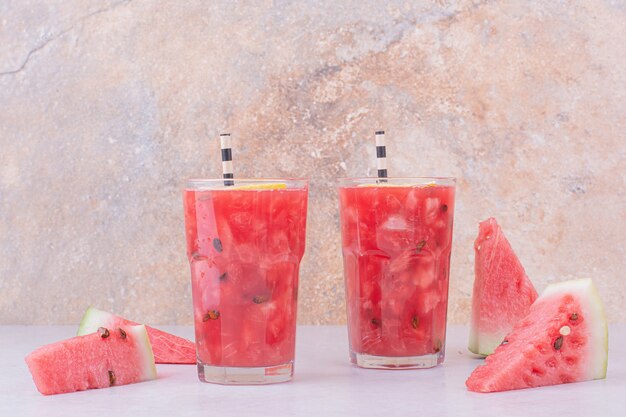 Rodajas de sandía roja con dos vasos de jugo