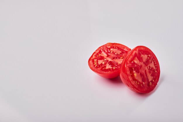 Rodajas de tomate aisladas en gris, vista de ángulo.