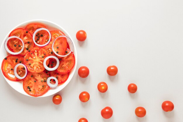 Rodajas de tomate y cebolla en placa sobre fondo blanco.