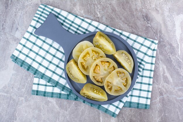 Rodajas de tomate fermentado sobre tablero oscuro con mantel.