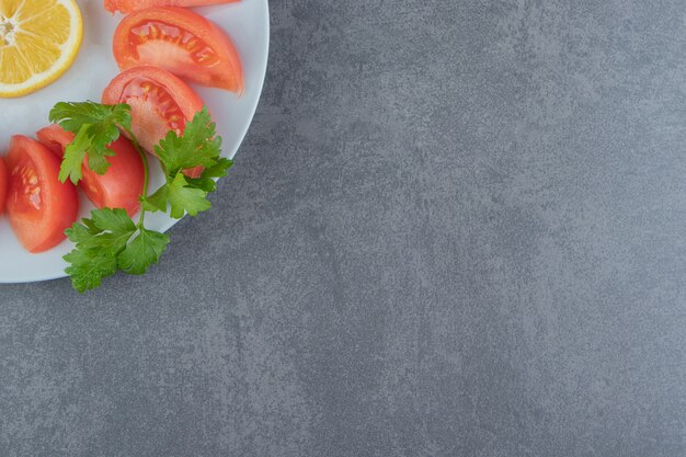 Rodajas de tomates frescos y perejil en un plato blanco.