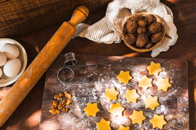 Foto gratuita rodillo y cortadores de galletas cerca de galletas crudas e ingredientes