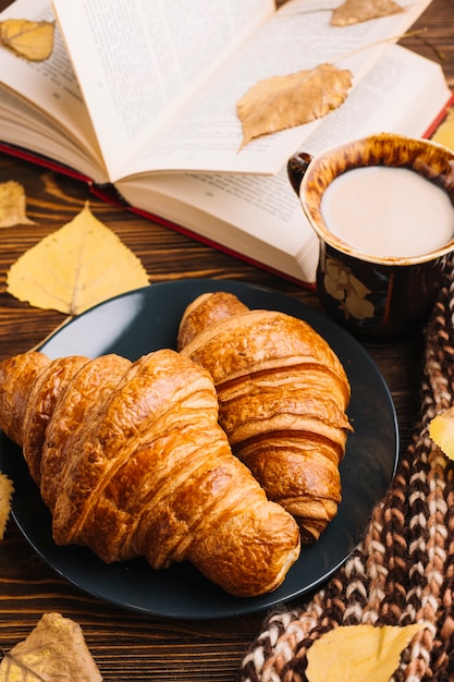 Foto gratuita roissants de primer plano cerca de la bebida y el libro