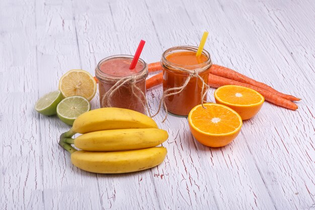 Rojo y naranja detox cócteles se encuentra en la mesa blanca con frutas