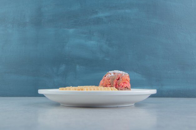 Roles de gofres en rodajas dulces con pastel en un plato blanco.