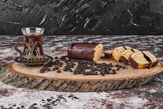 Rollcake de chocolate con bebida sobre una tabla de madera.