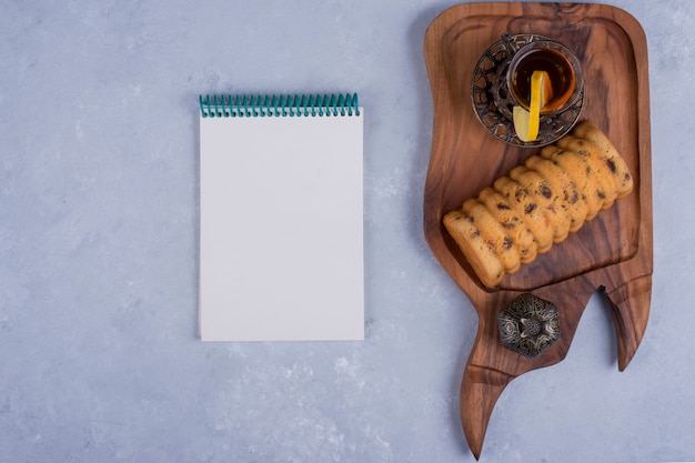 Rollcake servido con té Earl Grey en una bandeja de madera con un cuaderno a un lado