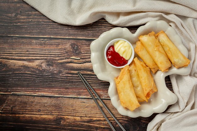 Rollitos de primavera con queso sobre fondo de madera oscura.