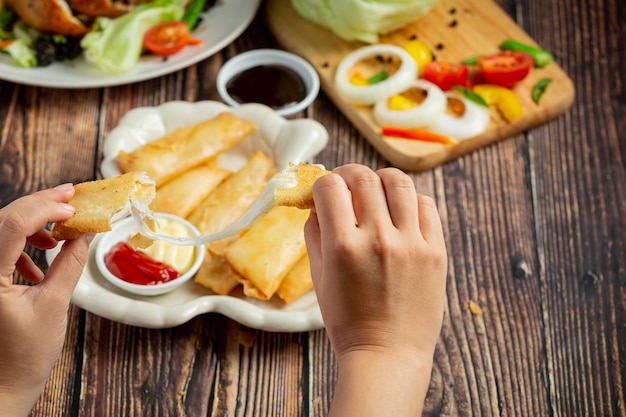 Rollitos de primavera con queso sobre fondo de madera oscura.