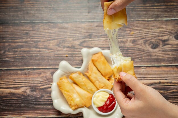 Rollitos de primavera con queso sobre fondo de madera oscura.