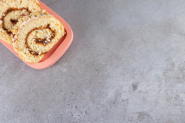 Rollo de bizcocho con crema de chocolate colocado sobre una tabla de madera