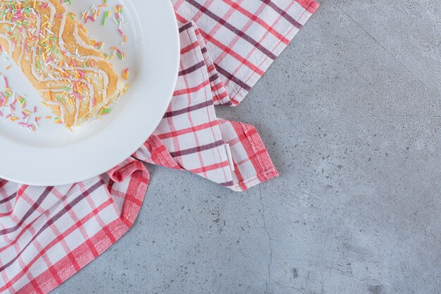 Rollo dulce con sabor a vainilla decorado con chispitas en un plato blanco.