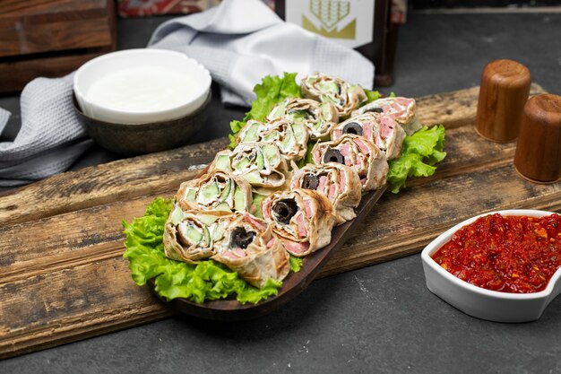 Rollo de ensalada en pan lavash sobre una hoja de lechuga servida con pasta de tomate