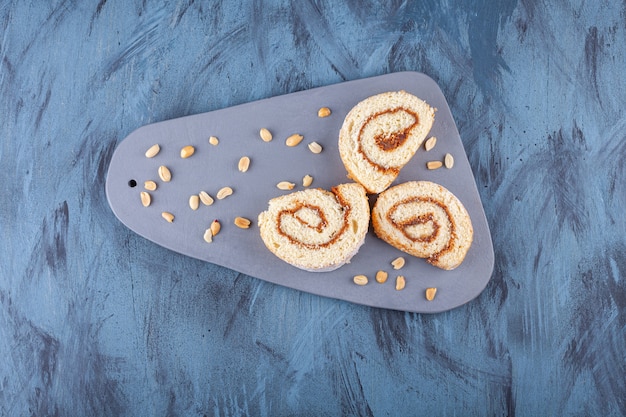 Rollo de galleta en rodajas con relleno de chocolate colocado sobre un tablero gris.