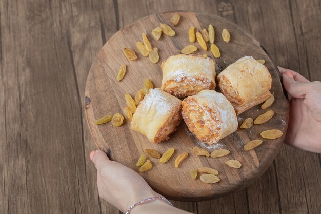 Rollo de galletas fritas con pasas blancas y rellenos dulces sobre una tabla de madera.