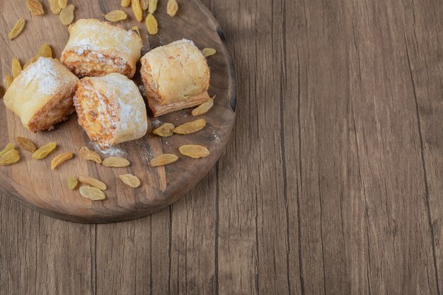 Rollo de galletas fritas con pasas blancas y rellenos dulces sobre una tabla de madera.