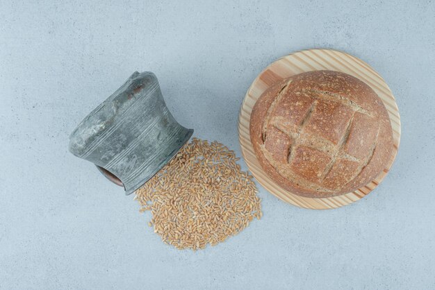 Rollo de pan de centeno sobre tabla de madera con taza de cebada