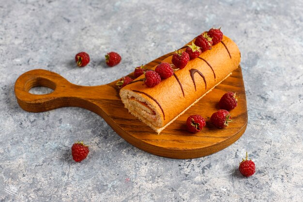 Rollo de pastel de frambuesa con frutos rojos frescos.