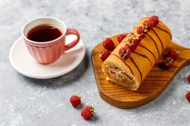 Rollo de pastel de frambuesa con frutos rojos frescos.