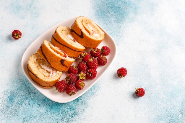 Rollo de pastel de frambuesa con frutos rojos frescos.