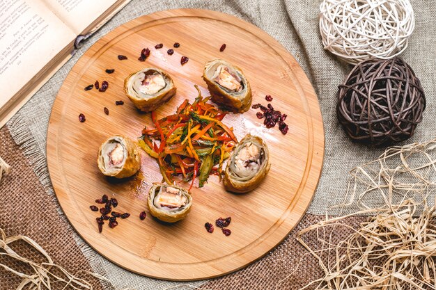 Rollo de pollo sobre tabla de madera mezclar pimiento con verduras vista superior