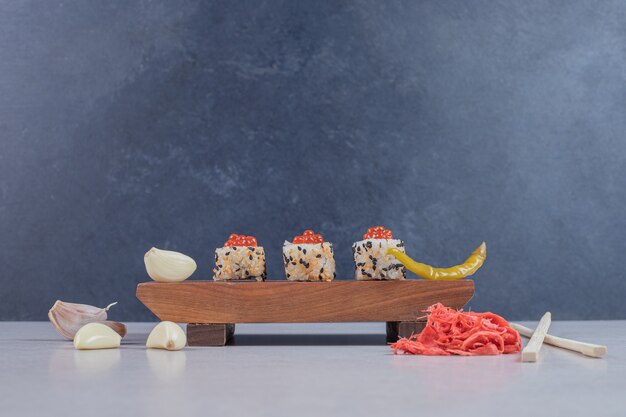 Foto gratuita rollo de sushi de alaska con jengibre encurtido en placa de madera.
