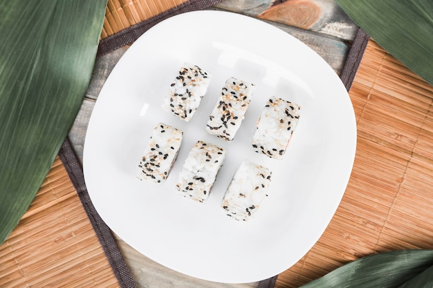 Rollo de sushi delicioso con las semillas de sésamo dispuestas en la placa blanca