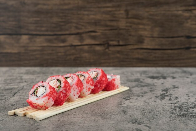 Rollo de sushi con palillos sobre un fondo de piedra.