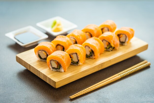 Rollo de sushi de salmón pescado carne maki en placa de madera