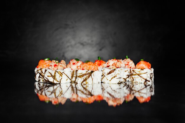 Rollo de sushi tobica hecho de nori, arroz marinado, queso, pepino, aguacate, salmón